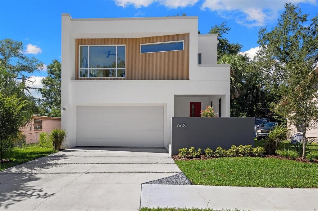A covered entryway features gray tile flooring, two wicker rocking chairs, and a bright red door — 668 NEWTON AVENUE S, ST PETERSBURG, FL