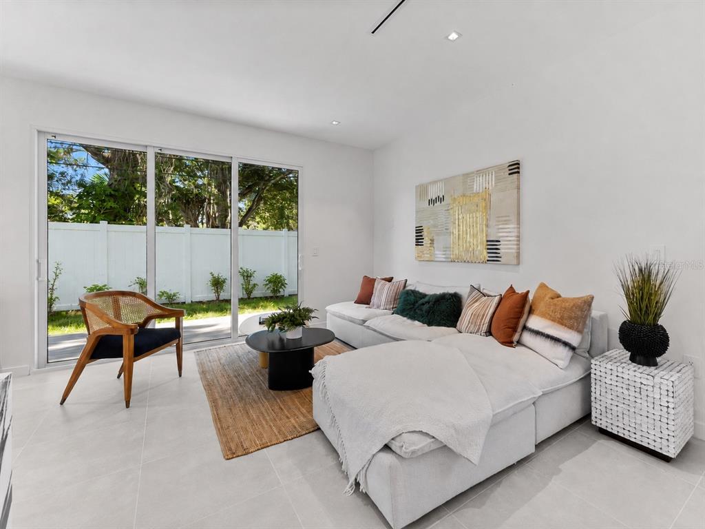 An open-concept kitchen and living area with a marble island, light tile floors, and sliding doors — 668 NEWTON AVENUE S, ST PETERSBURG, FL
