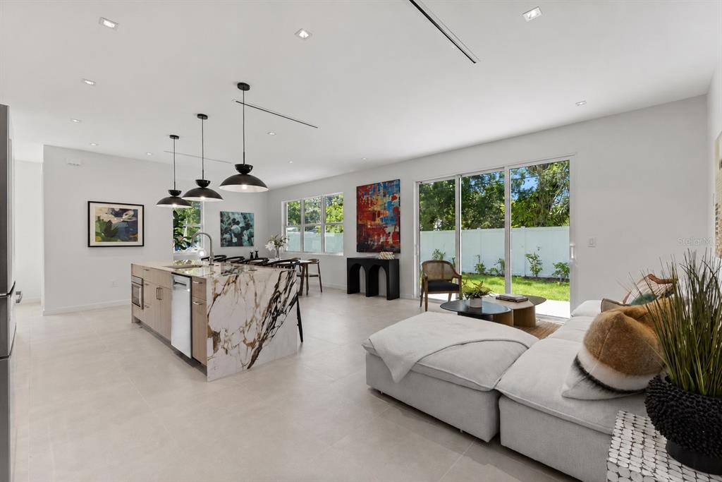 A modern living room features a white sectional sofa, two coffee tables, and neutral tile flooring — 668 NEWTON AVENUE S, ST PETERSBURG, FL
