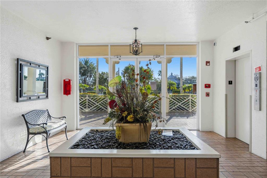 A lobby area features a central stone planter, a metal bench, and an elevator entrance — 200 HARBOR WALK DRIVE UNIT 322, PUNTA GORDA, FL