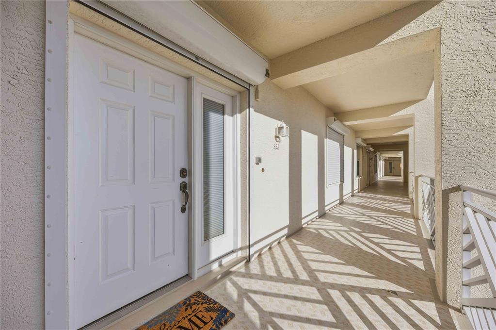 A white front door with a side window opens onto a covered outdoor apartment walkway — 200 HARBOR WALK DRIVE UNIT 322, PUNTA GORDA, FL