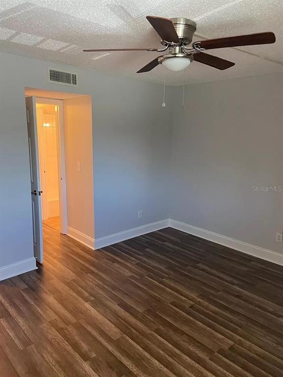 A bedroom features gray walls, wood-look flooring, a ceiling fan, and an open doorway — 6308 NEWTOWN CIRCLE UNIT 8B1, TAMPA, FL