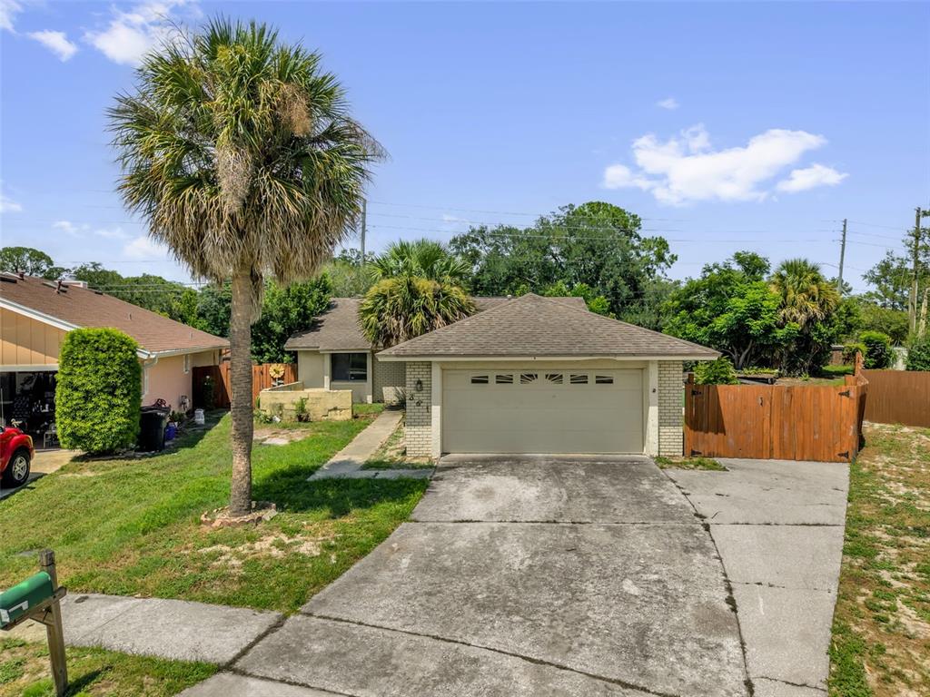A single-story house with a two-car garage, a concrete driveway, and a tall palm tree — 361 KANTOR BOULEVARD, CASSELBERRY, FL