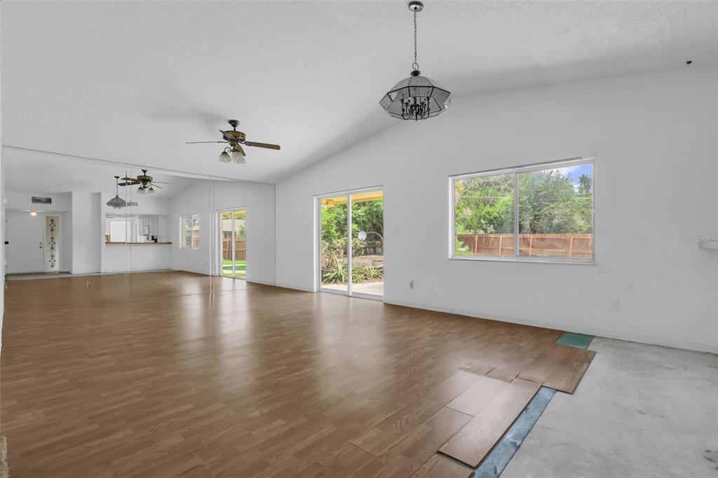 A living room features wood-look flooring, a mirrored wall, a ceiling fan, and sliding glass doors — 361 KANTOR BOULEVARD, CASSELBERRY, FL