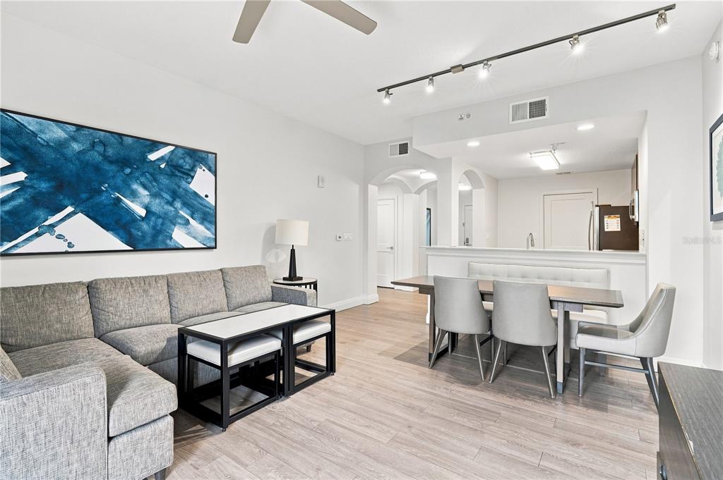 A living and dining area with gray furniture, light wood floors, and track lighting — 14501 GROVE RESORT AVENUE UNIT 3403, WINTER GARDEN, FL
