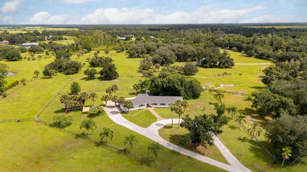 An aerial view shows a single-story house with a long driveway surrounded by grassy pastures — 5240 MYAKKA VALLEY TRAIL, SARASOTA, FL
