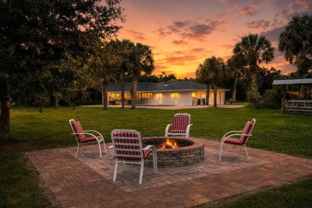 A fire pit with four chairs sits on a brick patio in front of a house — 5240 MYAKKA VALLEY TRAIL, SARASOTA, FL