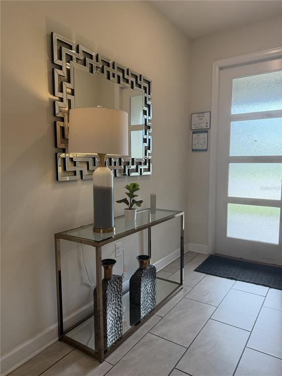 A modern entryway features a glass console table, a geometric mirror, and a table lamp — 2833 BOOKMARK DRIVE, KISSIMMEE, FL
