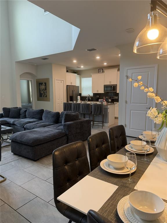An open-concept living room and kitchen feature a large sectional sofa and dining area — 2833 BOOKMARK DRIVE, KISSIMMEE, FL