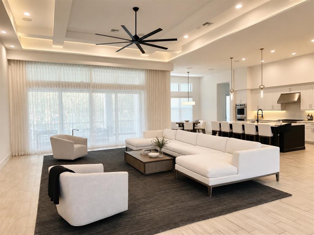 A modern open-concept living room features a large white sectional, two armchairs, and a kitchen — 5021 W HOMER AVENUE, TAMPA, FL
