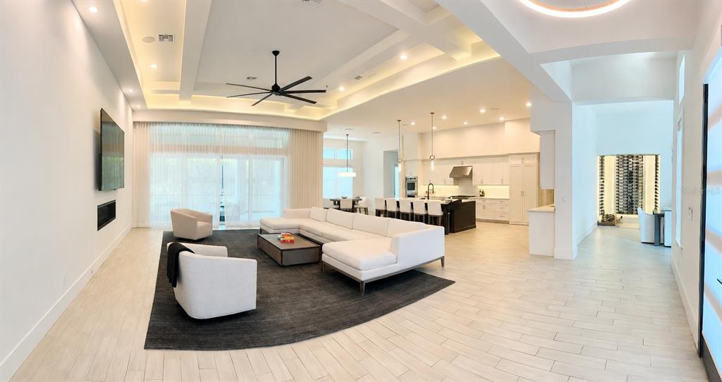 An open-concept living room and kitchen featuring white cabinetry, a large sectional, and tile flooring — 5021 W HOMER AVENUE, TAMPA, FL