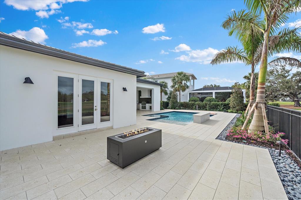 A modern patio features a rectangular fire pit, a small swimming pool, and palm trees — 3739 CALEDONIA LANE, SARASOTA, FL