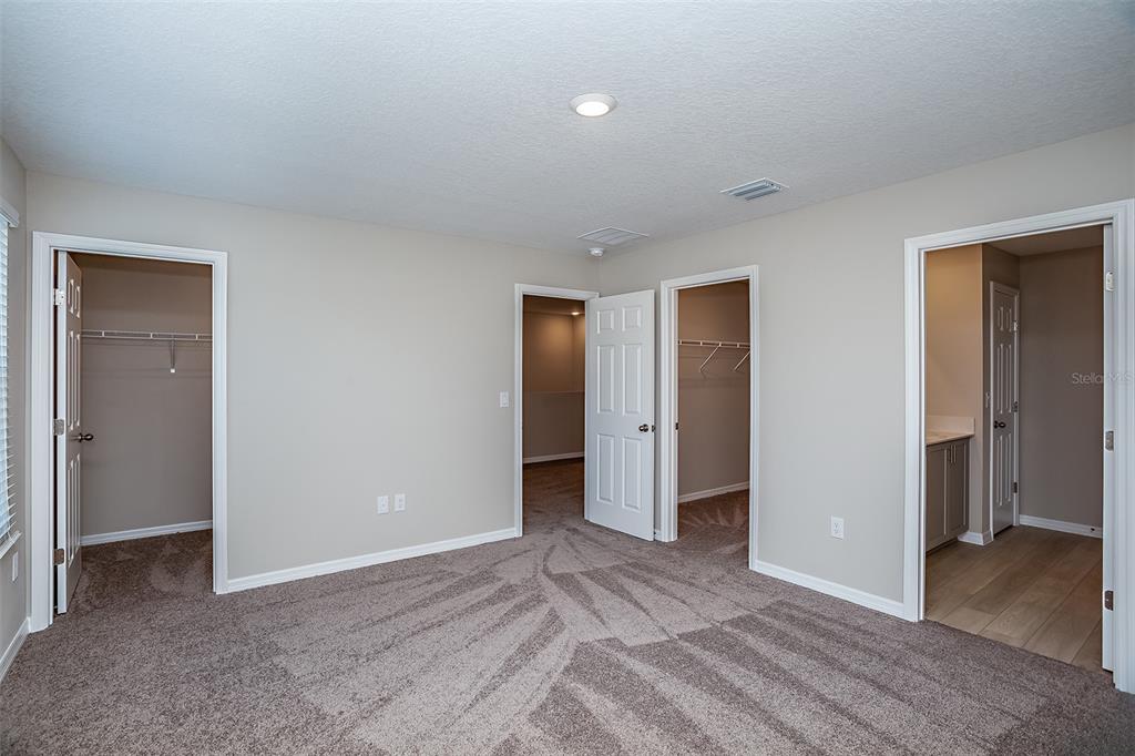A carpeted bedroom features three doorways leading to closets and an adjoining bathroom — 1743 VANILLA STREET, HAINES CITY, FL