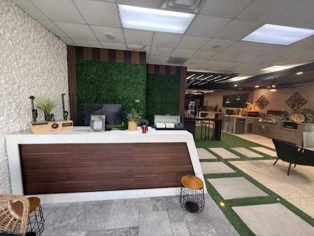 A modern reception area features a wood-paneled desk, a green wall, and stone flooring — 3852 L B MCLEOD ROAD, ORLANDO, FL