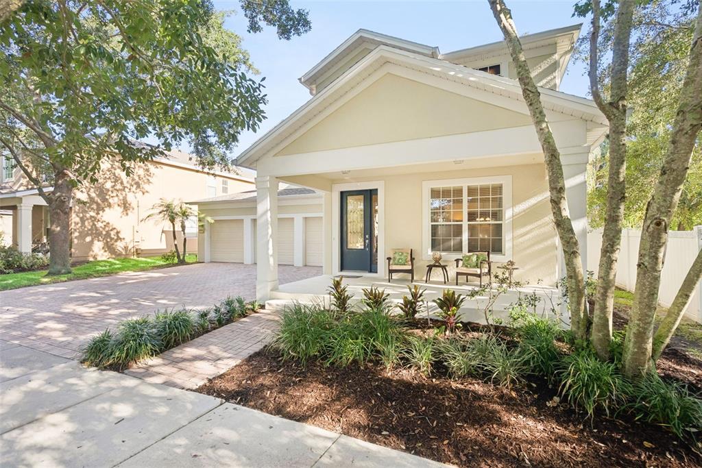 A light-colored house with a front porch, a brick driveway, and a three-car garage — 13239 JERVEY STREET, WINDERMERE, FL