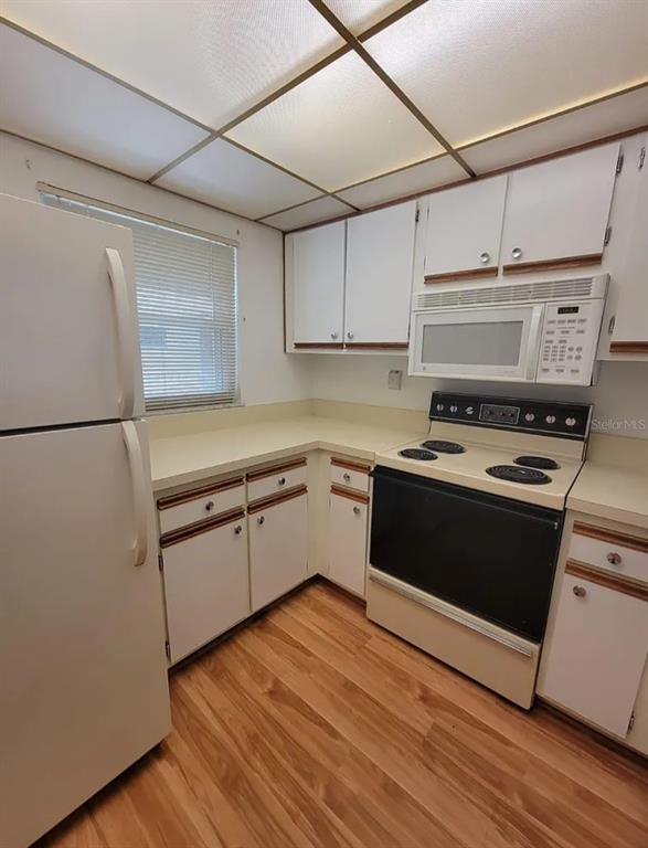 A kitchen features white cabinets, laminate countertops, a white refrigerator, and a black electric stove — 100 E KENTUCKY AVENUE UNIT 103D, DELAND, FL