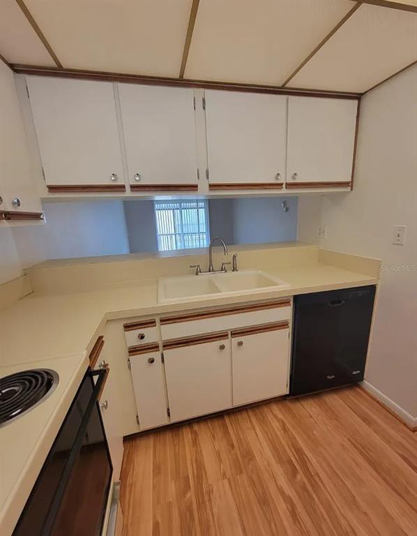 A kitchen features white cabinets with wood trim, a double sink, and a black dishwasher — 100 E KENTUCKY AVENUE UNIT 103D, DELAND, FL