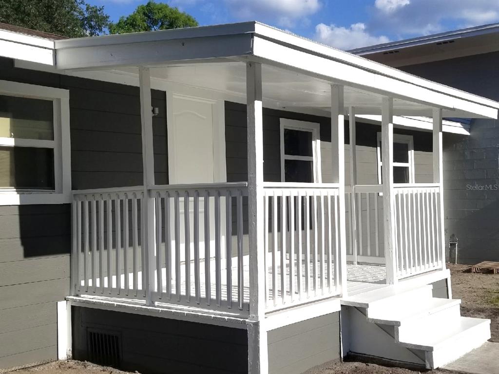 A white wooden porch with railings and stairs attached to a gray house exterior — 721 FOSTER AVENUE, WINTER GARDEN, FL