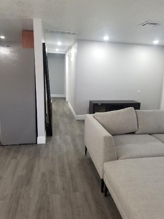 A living area with light gray flooring, a beige sectional sofa, and a hallway entrance — 721 FOSTER AVENUE, WINTER GARDEN, FL