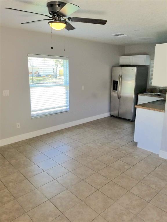 A kitchen and dining area with tile floors, a ceiling fan, and stainless steel refrigerator — 721 FOSTER AVENUE, WINTER GARDEN, FL