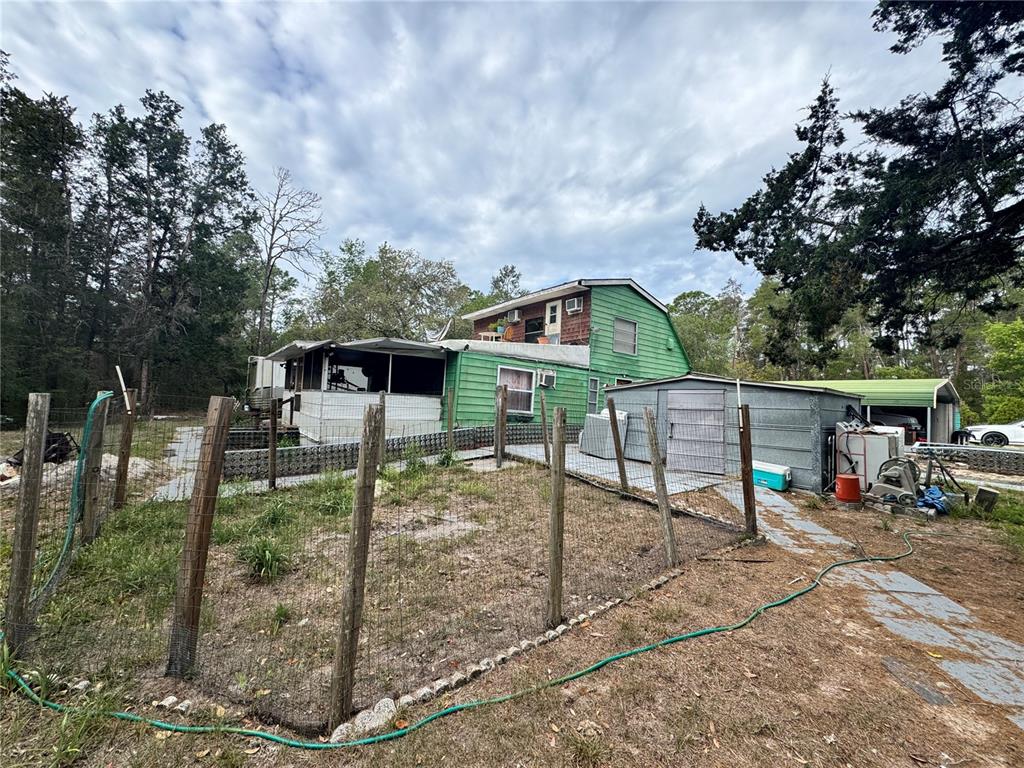 A green two-story house with a screened porch and a detached metal shed — 17528 COYOTE ROAD, HUDSON, FL