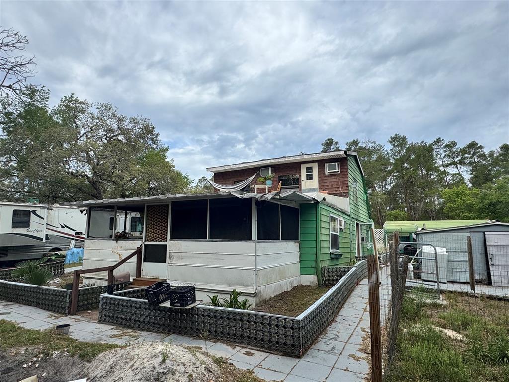 An exterior view of a two-story house with a screened-in porch and green siding — 17528 COYOTE ROAD, HUDSON, FL
