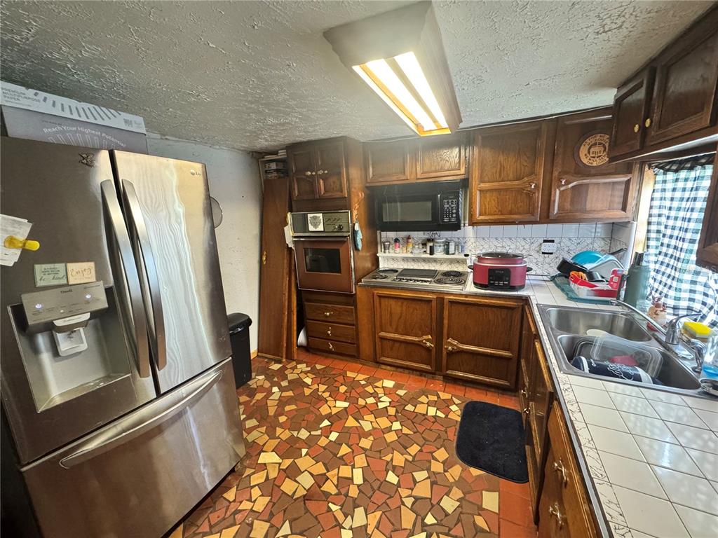 A kitchen with wood cabinets, stainless steel appliances, and a multi-colored mosaic tile floor — 17528 COYOTE ROAD, HUDSON, FL