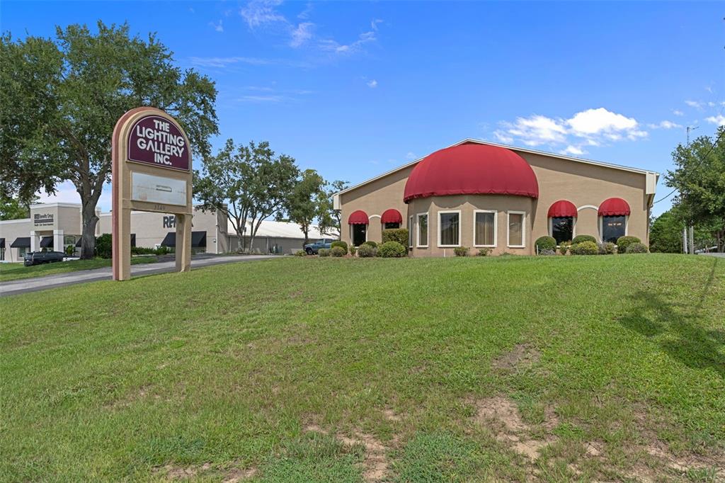 A commercial building with a large red dome awning sits on a grassy hill — 5149 MARINER BOULEVARD, SPRING HILL, FL