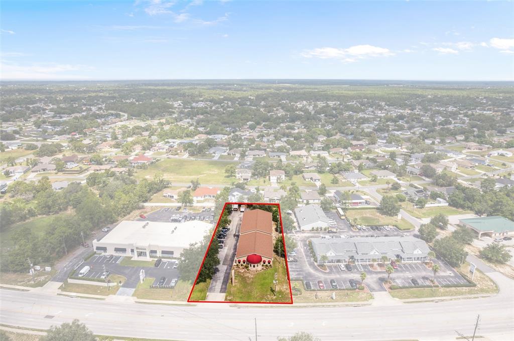 An aerial view shows a commercial building highlighted in red, situated between two parking lots — 5149 MARINER BOULEVARD, SPRING HILL, FL