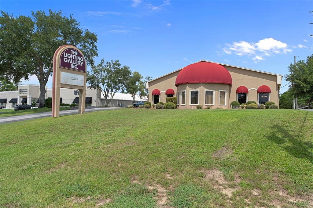 A commercial building with a large red dome awning sits on a grassy hill — 5149 MARINER BOULEVARD, SPRING HILL, FL