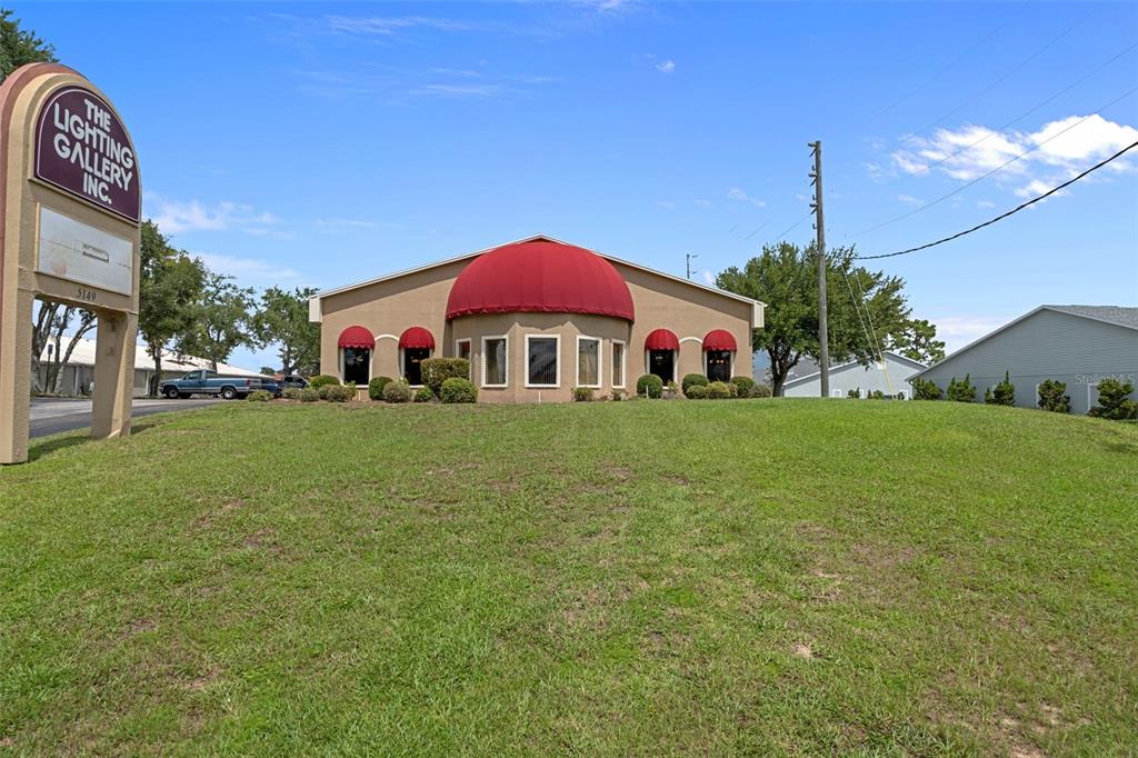 A commercial building with a large red dome and matching awnings sits on a grassy lot — 5149 MARINER BOULEVARD, SPRING HILL, FL