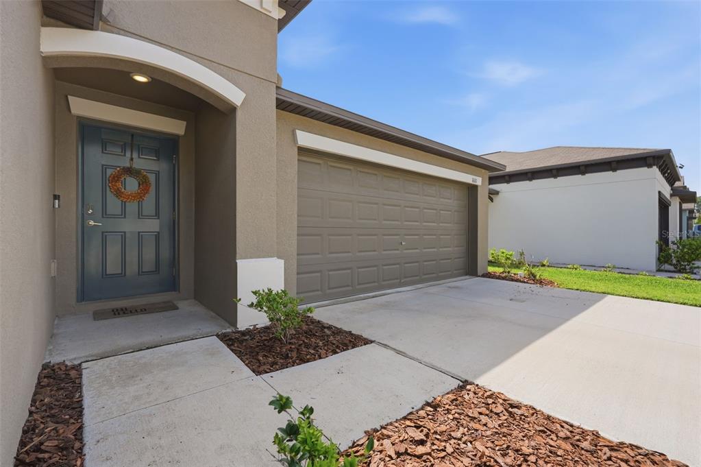 A beige house exterior features a blue front door, a garage, and a concrete driveway — 1681 RED LOOP, LAKELAND, FL