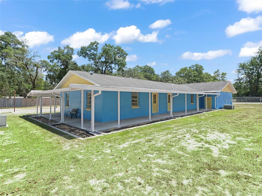 A blue, single-story house with a yellow gable and a long, covered front porch — 9475 SE 35TH COURT, OCALA, FL