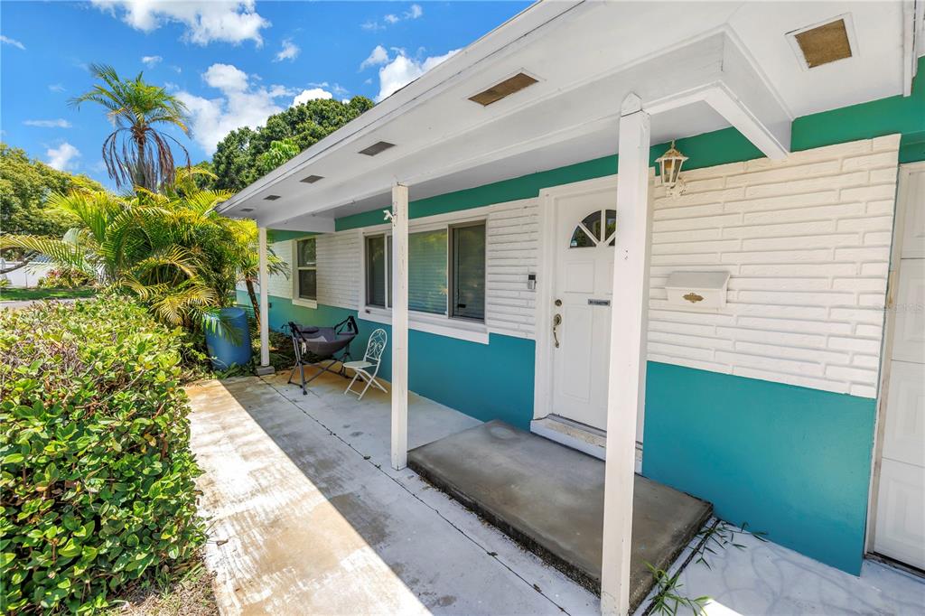 A teal and white exterior wall features a covered concrete porch and a front door — 6195 28TH AVENUE N, ST PETERSBURG, FL