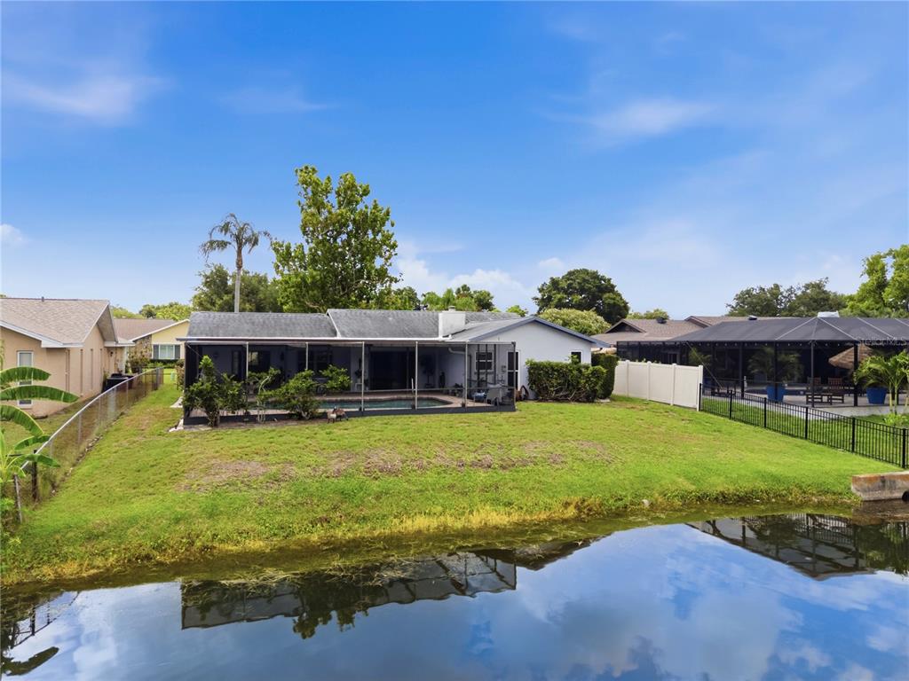 A single-story house with a screened-in pool and patio sits along a canal — 10744 97TH STREET, LARGO, FL