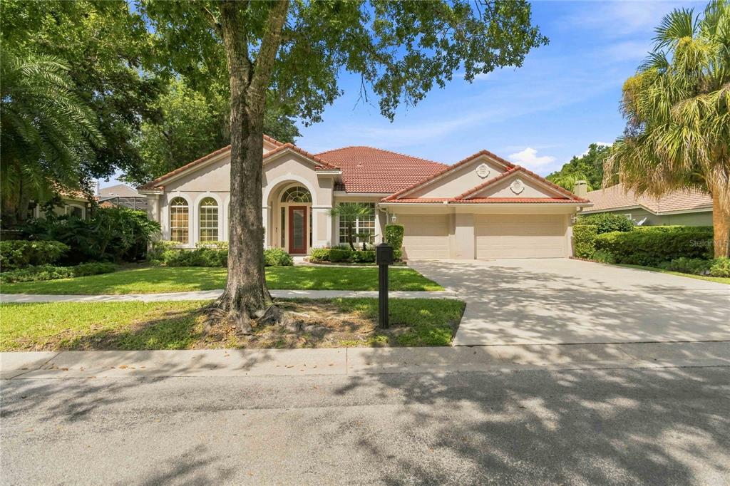 A single-story house with a red tile roof, beige stucco exterior, and a two-car garage — 1038 WESTBURY WAY, LAKE MARY, FL