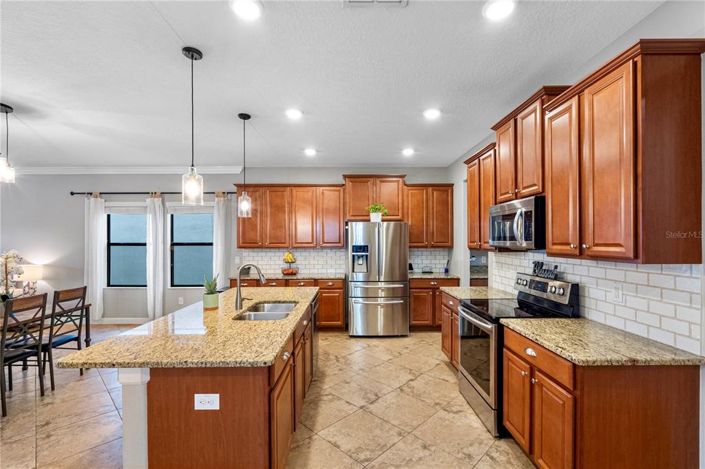 A kitchen features wood cabinets, granite countertops, stainless steel appliances, and a central island — 19343 PADDOCK VIEW DRIVE, TAMPA, FL