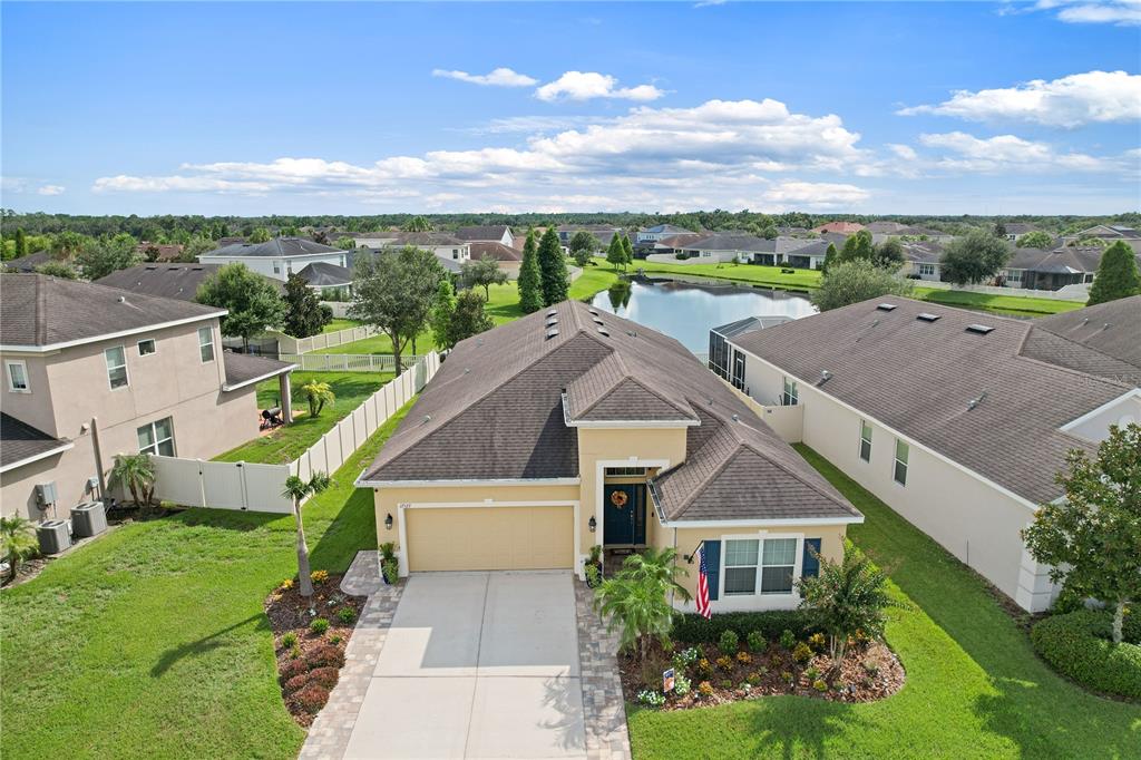 A screened-in patio features wicker furniture, a fire pit, and string lights overlooking a pond — 17527 BRIGHT WHEAT DRIVE, LITHIA, FL