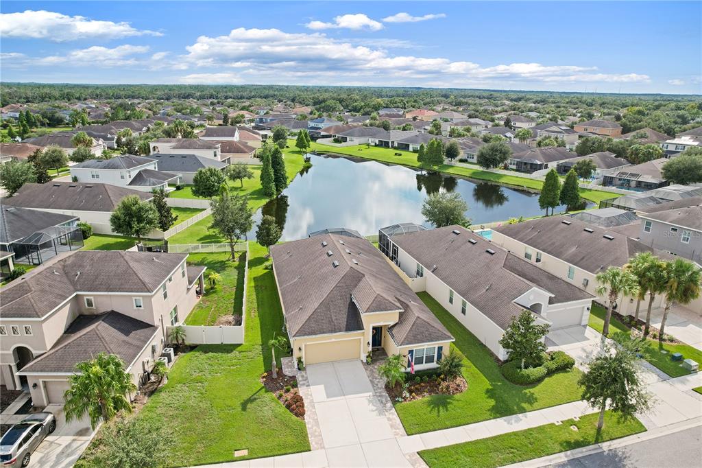 An aerial view shows a tan single-story house with a two-car garage and a pond — 17527 BRIGHT WHEAT DRIVE, LITHIA, FL