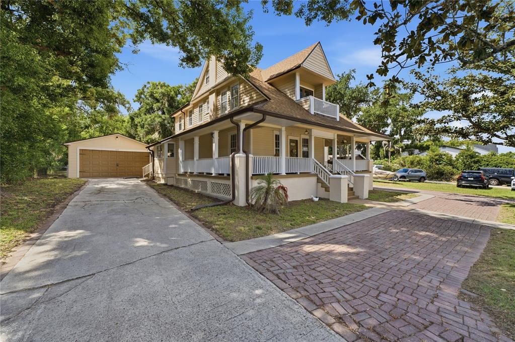 A two-story yellow house with a wrap-around porch, detached garage, and brick driveway — 535 W OSCEOLA STREET, CLERMONT, FL