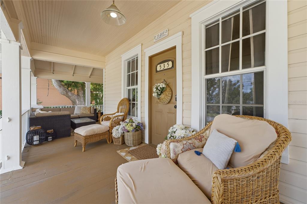 A covered front porch features wicker furniture, a brown door, and light-colored siding — 535 W OSCEOLA STREET, CLERMONT, FL