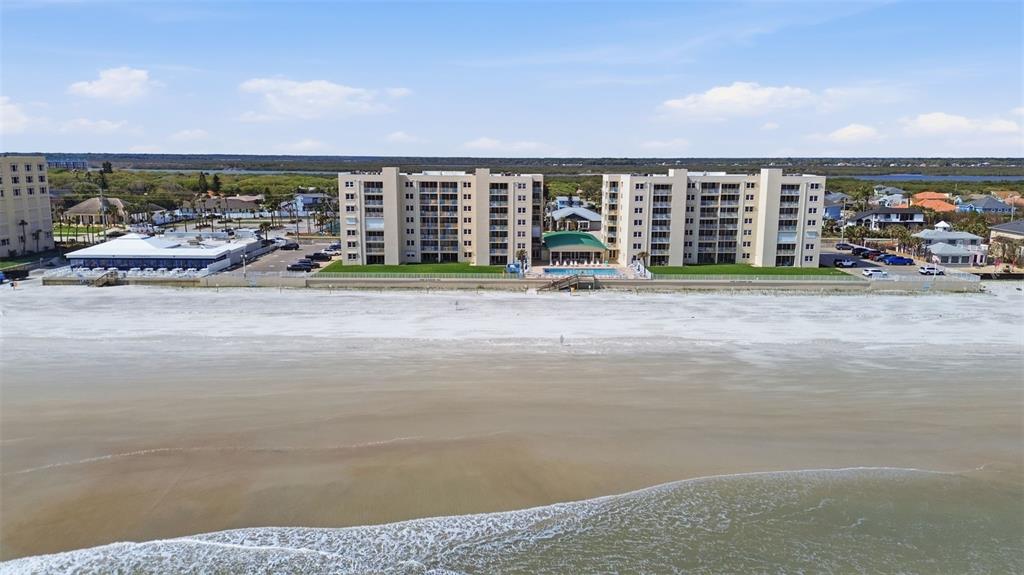 An aerial view of a multi-story beachfront condominium complex with a pool and parking lot — 4495 S ATLANTIC AVENUE UNIT 501, PORT ORANGE, FL