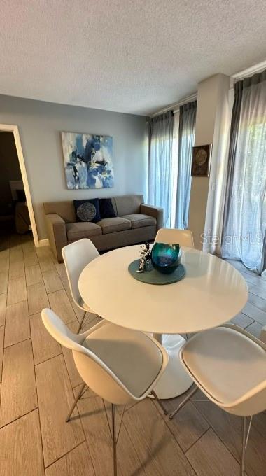 A dining area with a round white table and chairs sits before a living room sofa — 6165 CARRIER DRIVE UNIT 3105, ORLANDO, FL