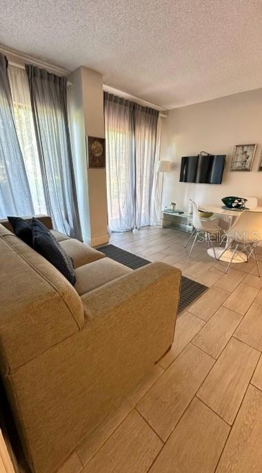 A living room with a beige sofa, tile flooring, and a dining area near a window — 6165 CARRIER DRIVE UNIT 3105, ORLANDO, FL