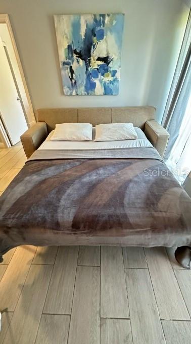 A pull-out sofa bed with a brown blanket sits in a room with light-colored tile floors — 6165 CARRIER DRIVE UNIT 3105, ORLANDO, FL