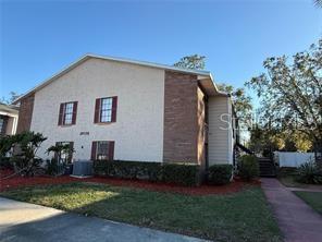 A two-story apartment building features a light-colored stucco facade with brick accents and brown shutters — 21038 VOYAGER BOULEVARD UNIT 4, LAND O LAKES, FL