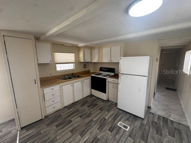 A kitchen features white cabinets, a white refrigerator, a black stove, and wood-look flooring — 7130 COMMONS BOULEVARD, PORT RICHEY, FL
