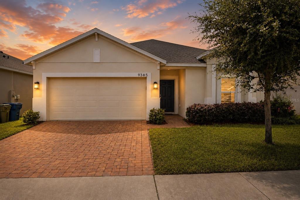 A single-story house with a beige stucco exterior, a two-car garage, and a brick driveway — 9385 LA SALLE STREET, GROVELAND, FL