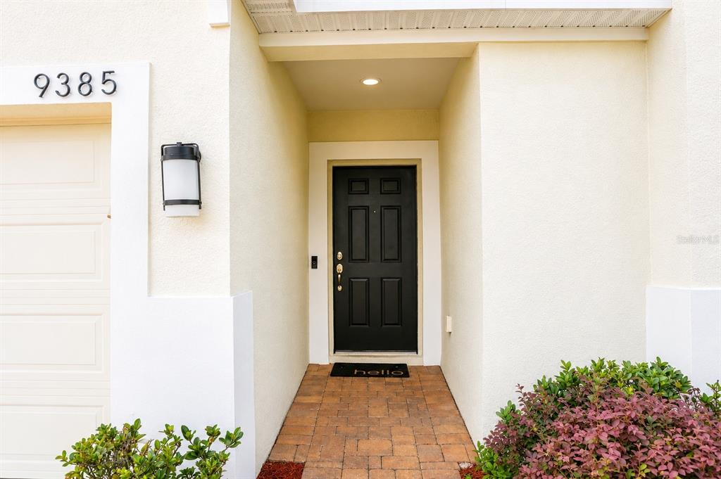 The exterior of a home features a black front door, a paved walkway, and a garage — 9385 LA SALLE STREET, GROVELAND, FL