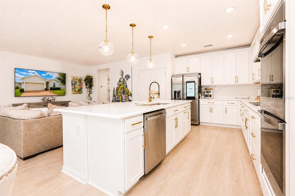 A modern kitchen features white cabinetry, a large island with a dishwasher, and stainless appliances — 9385 LA SALLE STREET, GROVELAND, FL